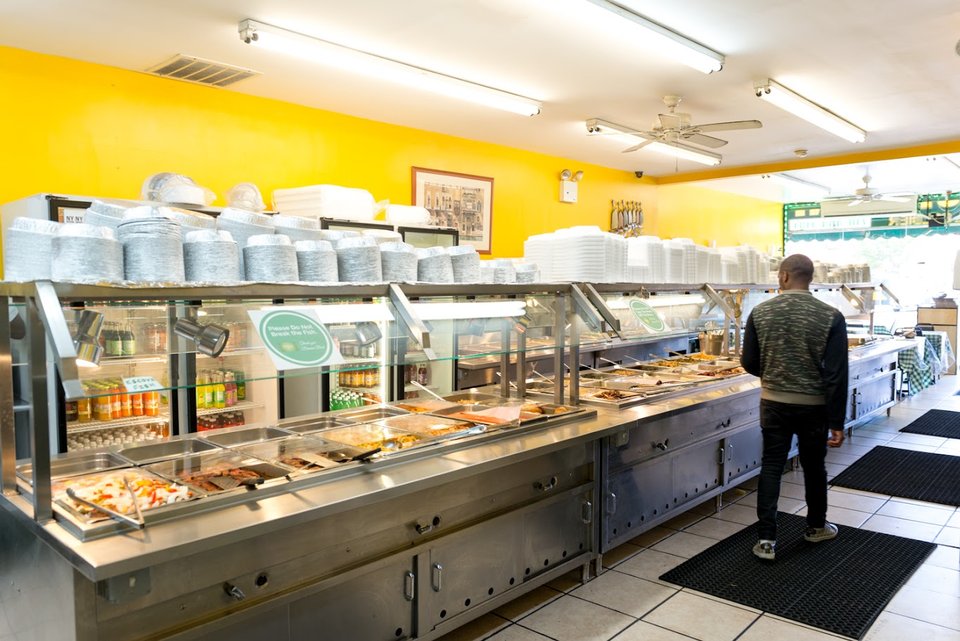 Caribbean restaurant counter with buffet-style dishes.